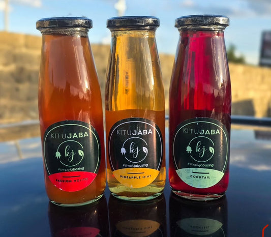 Three bottles of Kitujaba drinks on a reflective surface with a blurred outdoor background